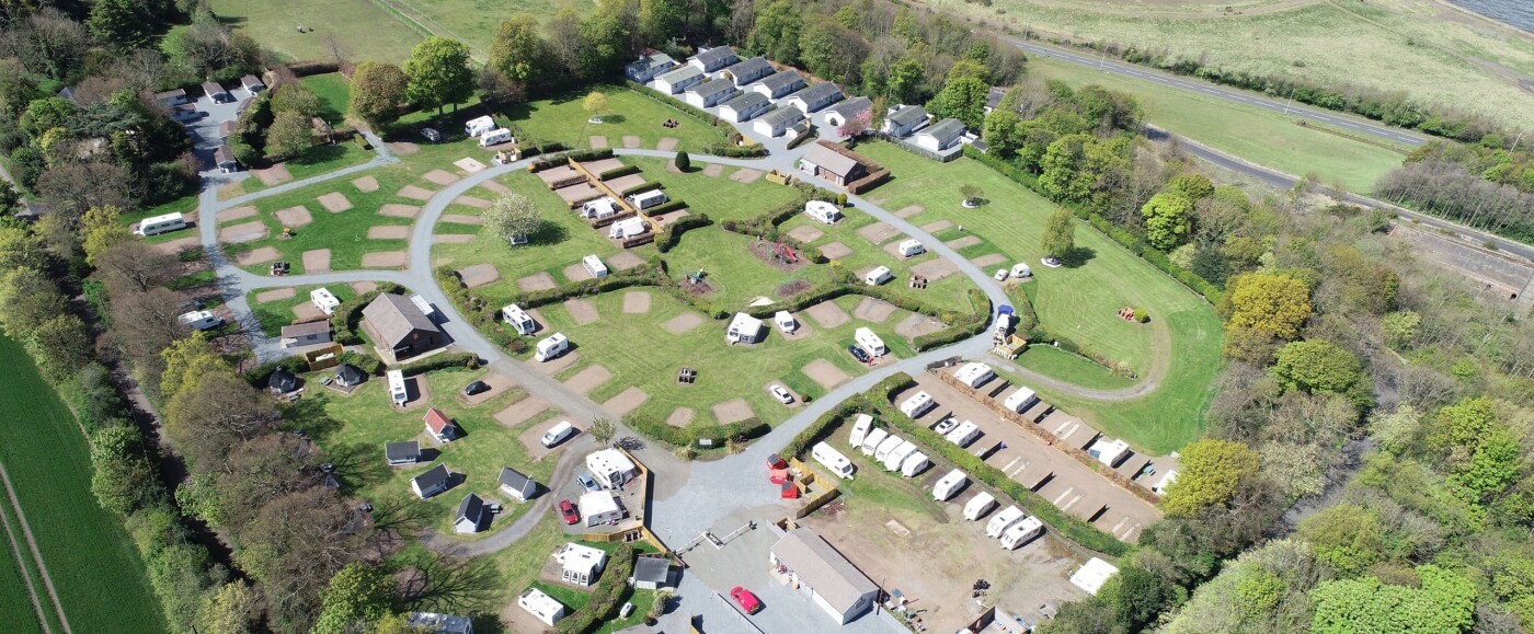 Vista aérea del camping Drummohr con parcelas de caravanas, zonas de glamping y campos verdes