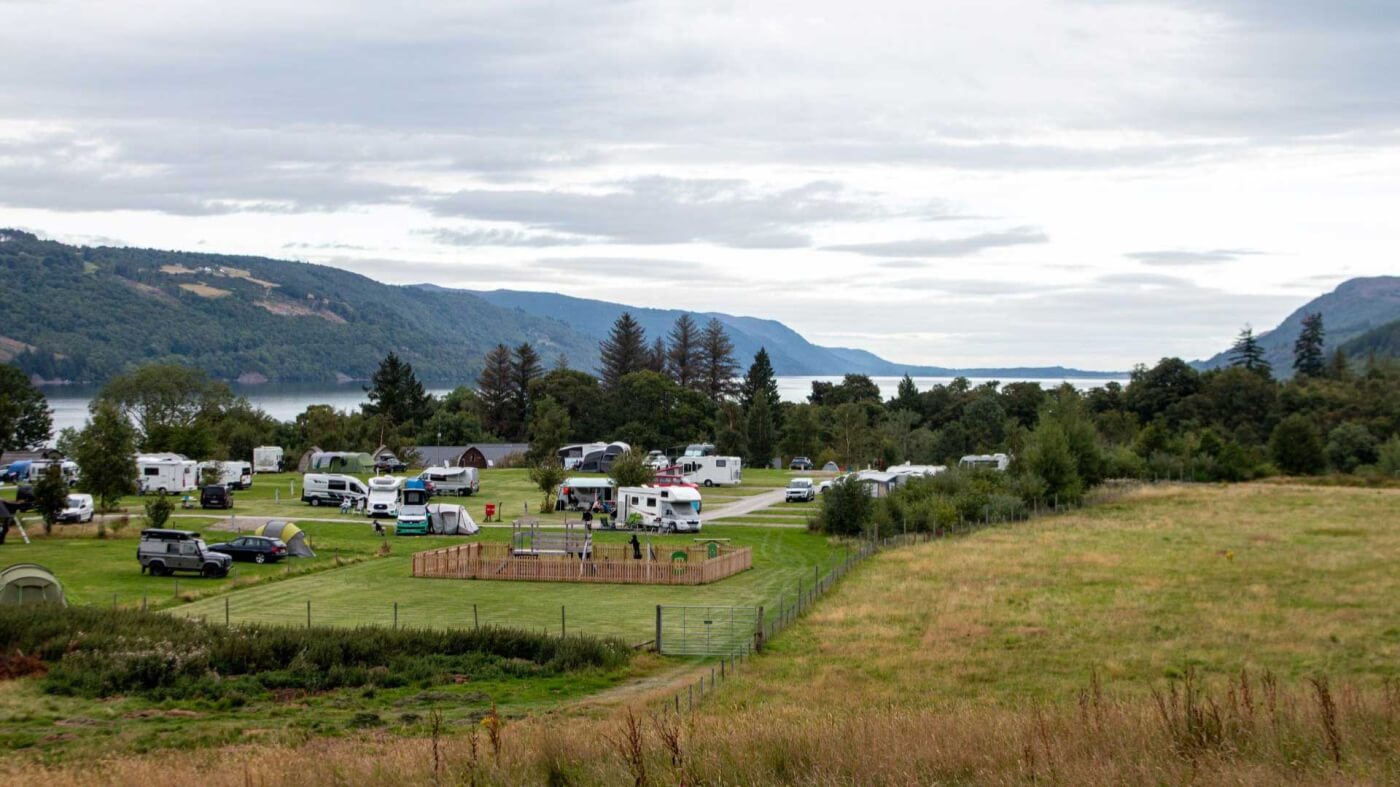 Camping con autocaravanas y caravanas junto al Loch Ness con montañas al otro lado del lago