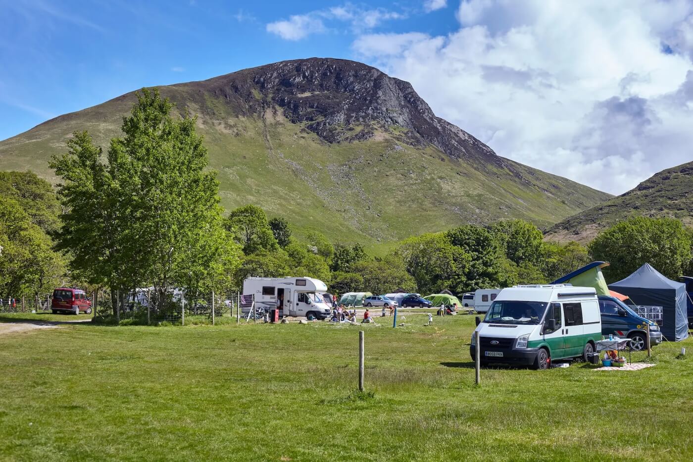 Autocaravanas y furgonetas en el Lochranza Caravan and Campsite de Arran con una montaña imponente al fondo