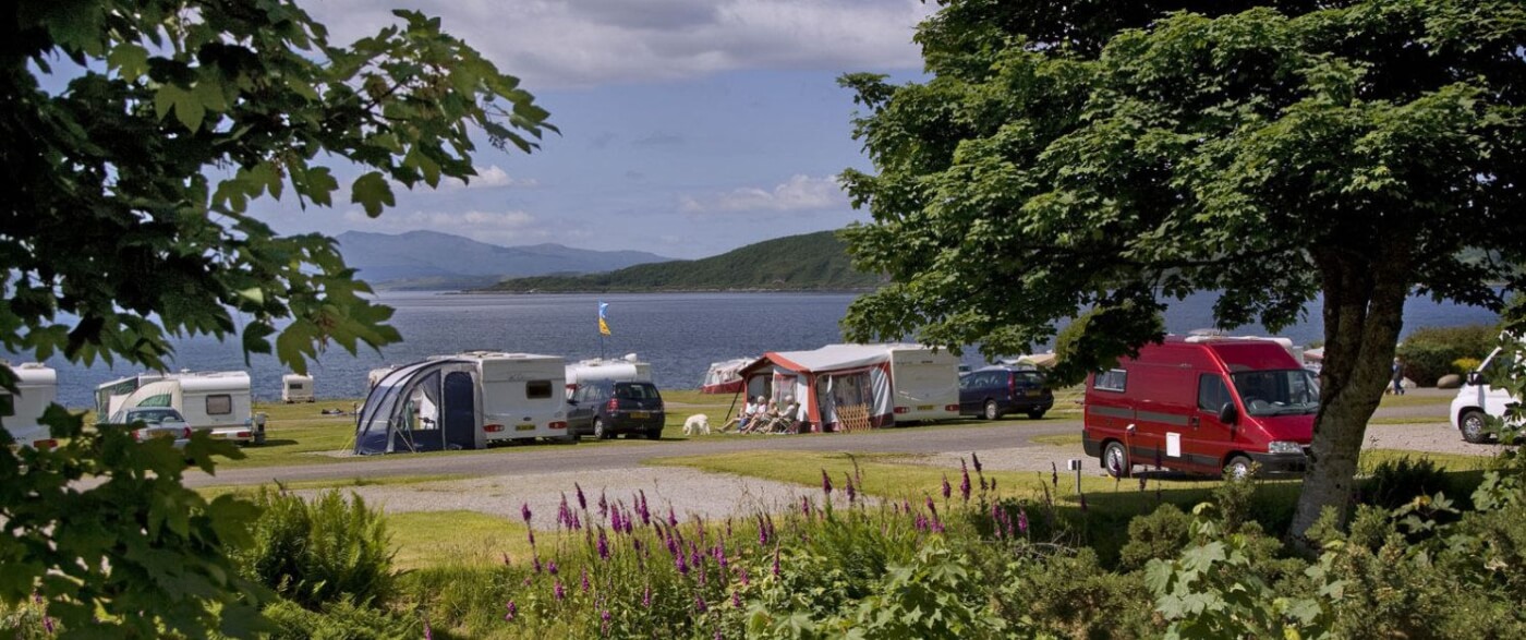 Caravanas y autocaravanas en North Ledaig Caravan Park con vistas al mar y colinas en día soleado