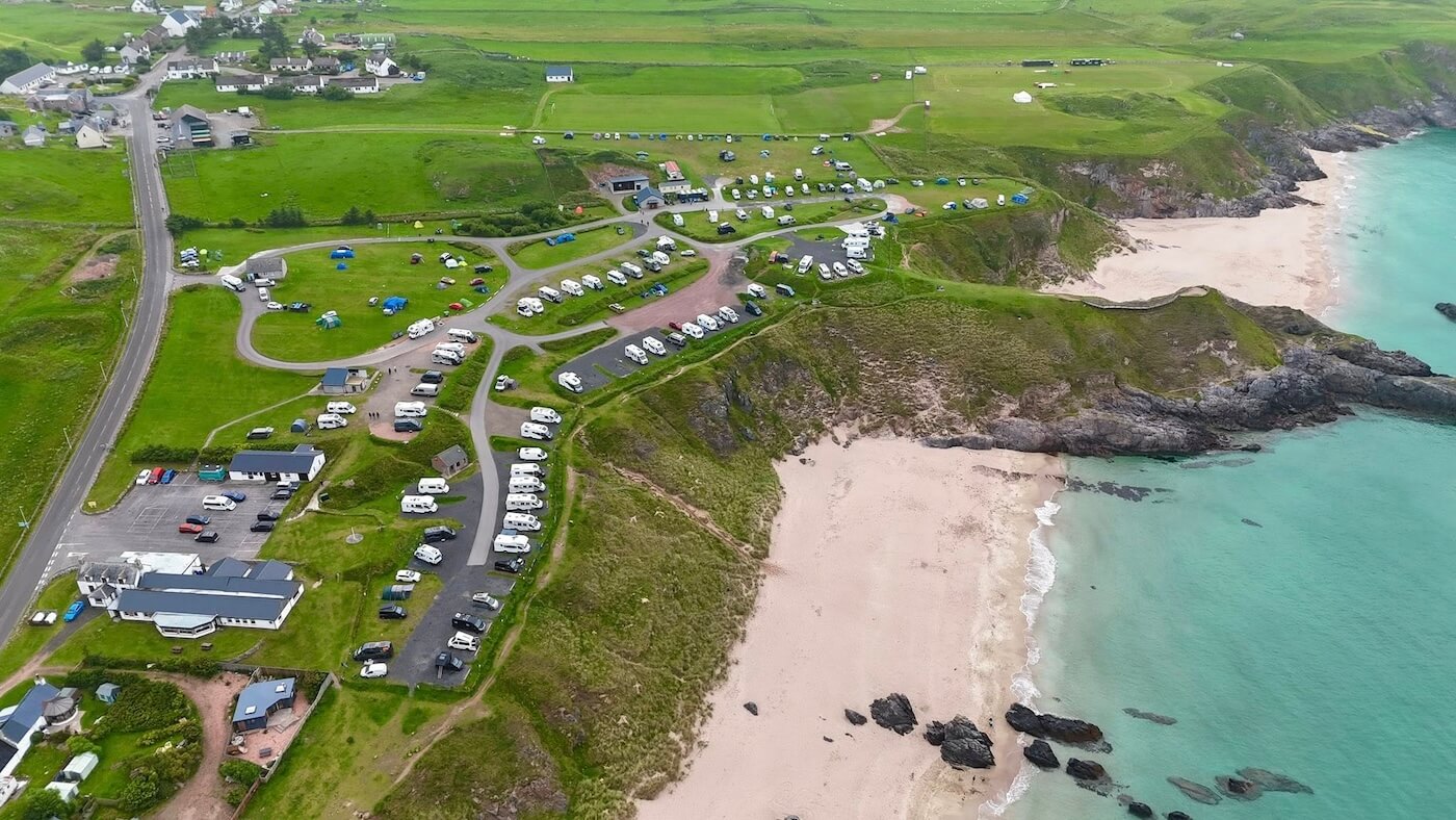 Vista aérea del Sango Sands Oasis junto a una playa de arena con aguas turquesas en el norte de Escocia