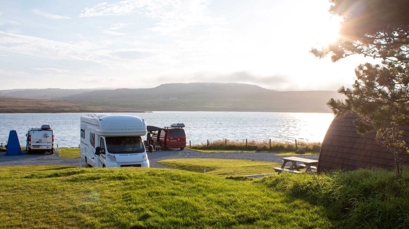 Autocaravanas en el Skye Camping and Caravanning Club Site frente a la bahía con un pueblo al fondo