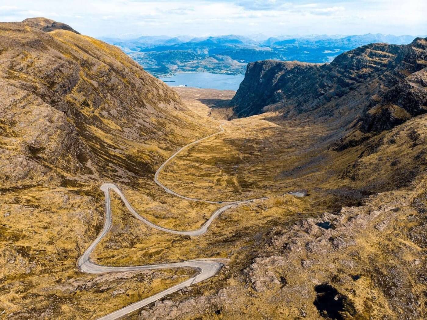 Vista a&eacute;rea de la carretera Bealach na B&agrave; entre monta&ntilde;as en las Highlands de Escocia